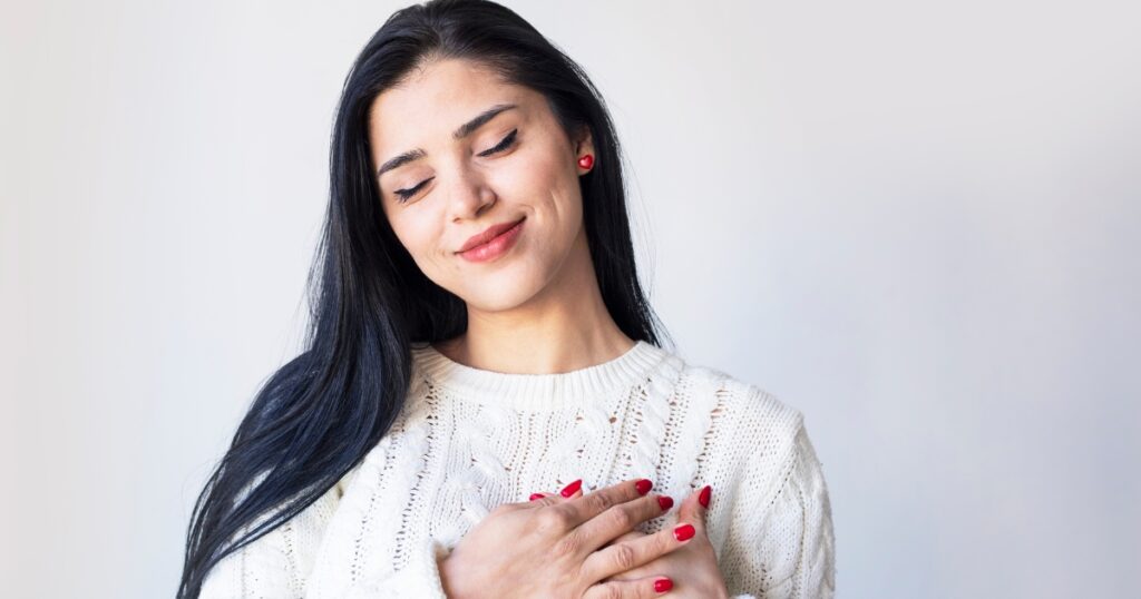 Woman holds her hands over her heart smiling